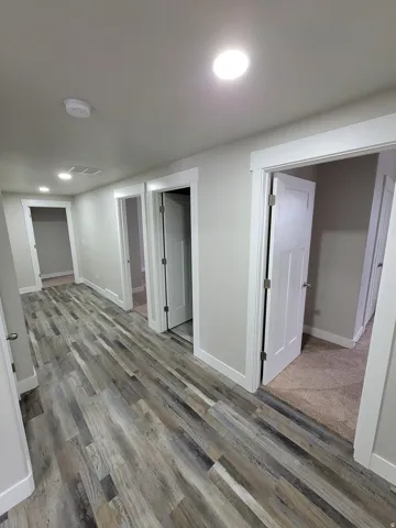 Hallway featuring wood-finish flooring, recessed lighting, white trim, and neutral wall tones