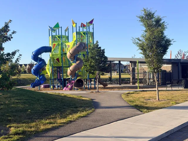 Modern playground structure featuring multiple slides, climbing elements, and colorful flags