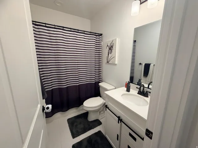 Bathroom featuring a white vanity with a single basin sink, white countertop, and dark-finish fixtures