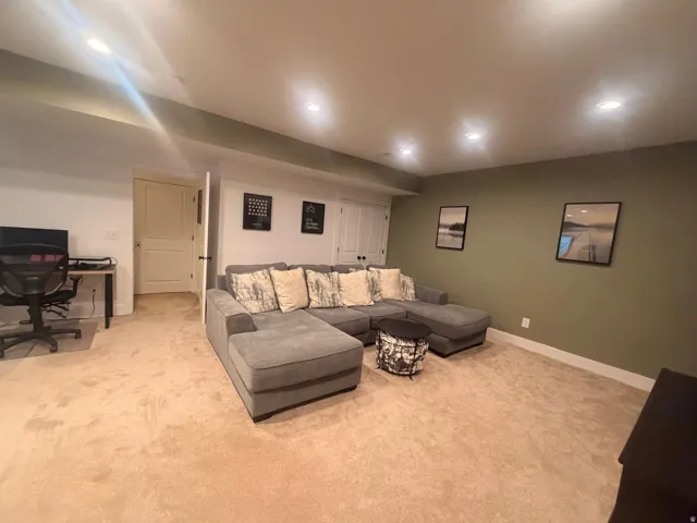 Carpeted lower-level room featuring recessed lighting, a neutral-toned accent wall, and white trim