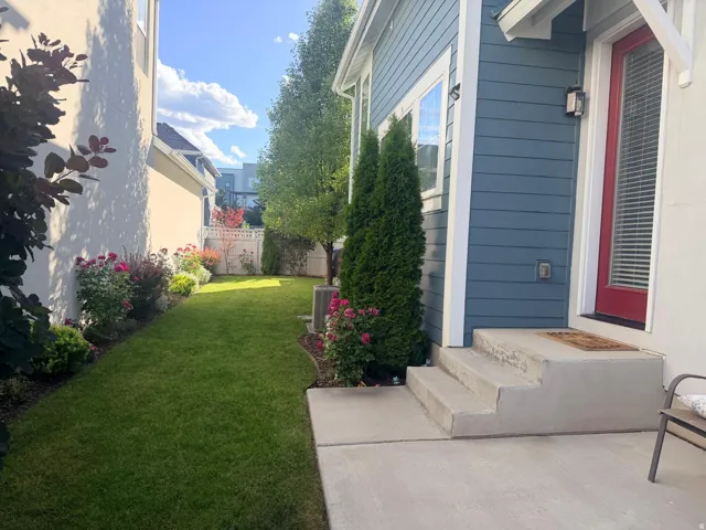 Manicured lawn area with established plantings and a concrete patio