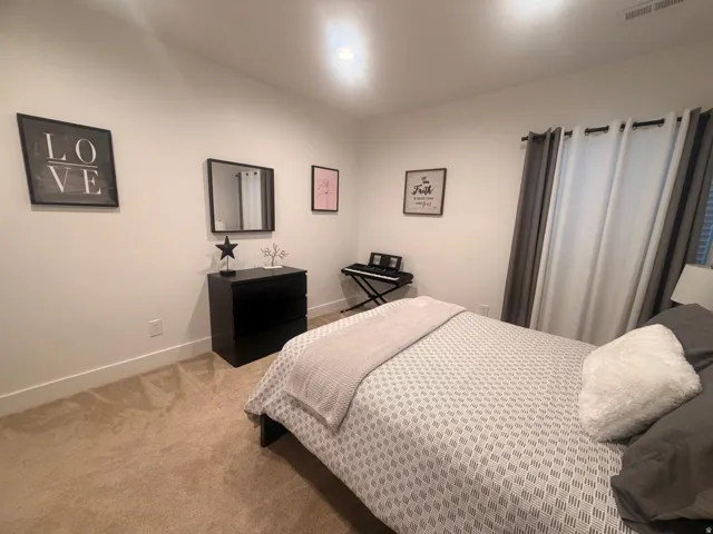 Carpeted room featuring a window with curtain rod and drapes, white baseboards, and overhead lighting