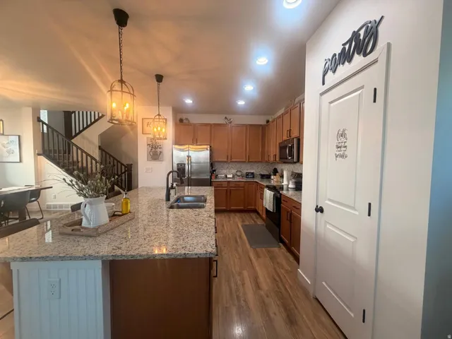 Kitchen featuring wood-finish flooring, granite countertops, and warm-toned cabinetry