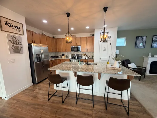 Open-concept kitchen with wood-finish flooring, recessed lighting, and granite countertops