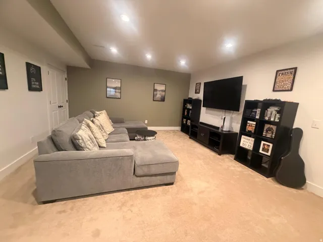 Carpeted lower level recreation space featuring recessed lighting, a neutral color palette, and white baseboards