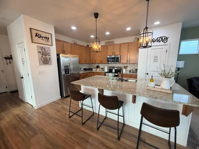 Kitchen with granite-finish countertops, wood-finish flooring, and warm-toned cabinetry
