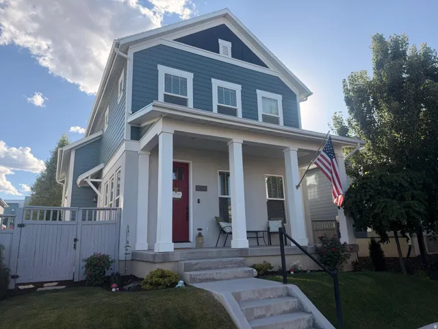 Two-story residence featuring a covered front porch with four white columns, a red entry door, and light blue siding
