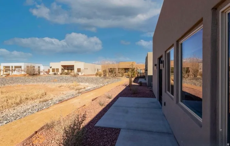 Stucco exterior with multiple windows, concrete patio, and exterior lighting fixtures