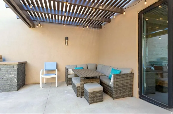Outdoor patio featuring a slatted wood pergola, built-in stone-clad counter, and concrete flooring