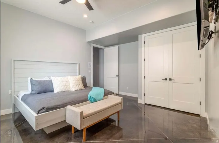 Polished concrete flooring, recessed lighting, ceiling fan, and double panel closet doors with modern hardware