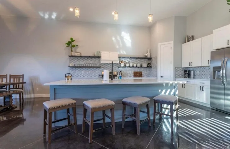 Kitchen featuring a spacious island, white cabinetry, integrated stainless steel appliances, open shelving, and pendant lighting