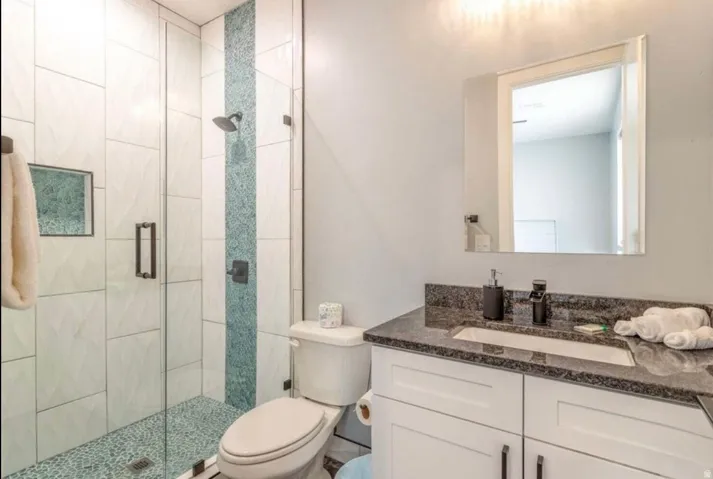 Glass-enclosed shower with a decorative tile inlay and pebble-style flooring