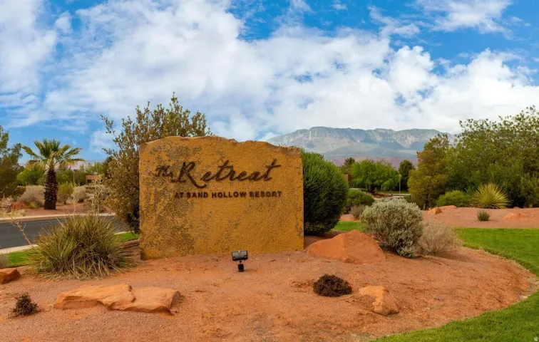 Stone monument sign featuring "The Retreat at Sand Hollow Resort" with mountainous terrain backdrop