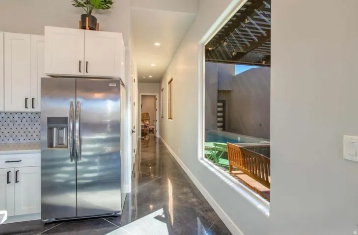 Kitchen featuring white cabinetry, a patterned tile backsplash, and a stainless steel side-by-side refrigerator