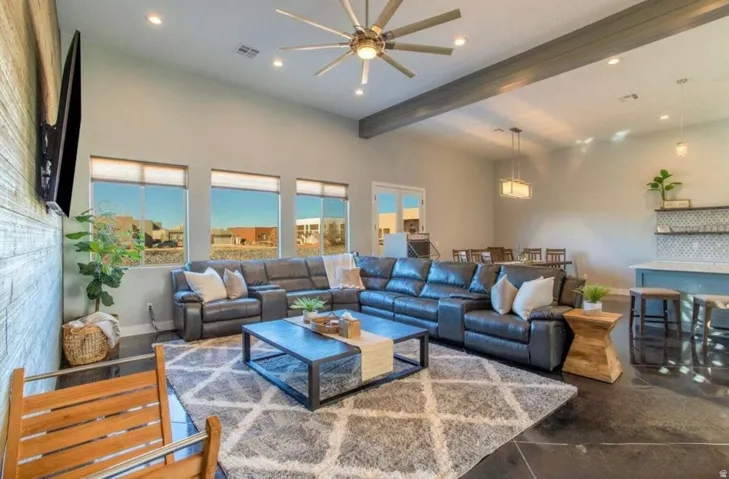 Vaulted ceiling with exposed beam, recessed lighting, wood-finish accent wall, polished concrete flooring, and a built-in wet bar with tiled backsplash