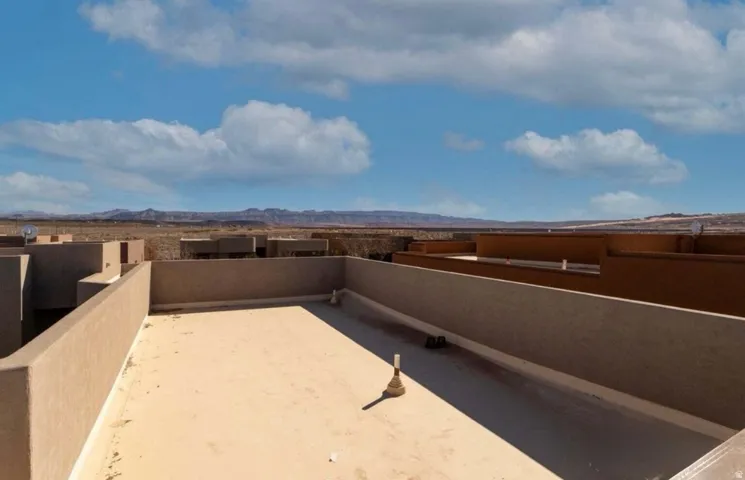 Rooftop patio with low perimeter walls and desert landscape