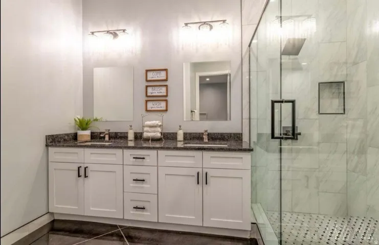 Double vanity with white cabinetry, dark countertop, and individual mirrors