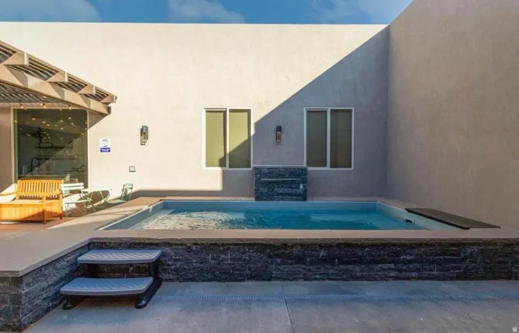 Private courtyard featuring a plunge pool with stone-clad exterior, integrated waterfall, and a surrounding concrete patio