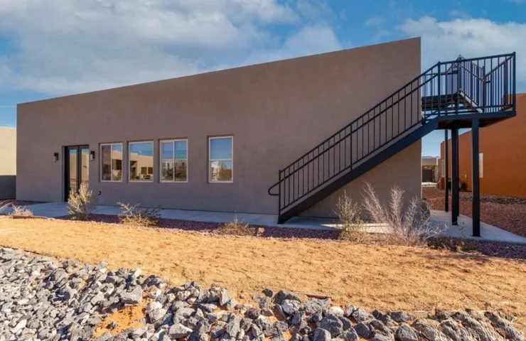 Stucco exterior with multiple windows, a glass-paned door, and an exterior metal staircase
