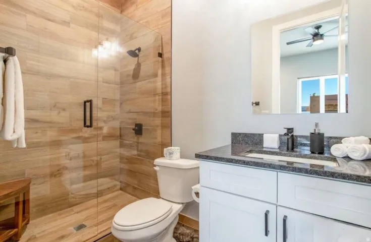 Glass-enclosed shower with wood-finish tile surround and dark bronze fixtures