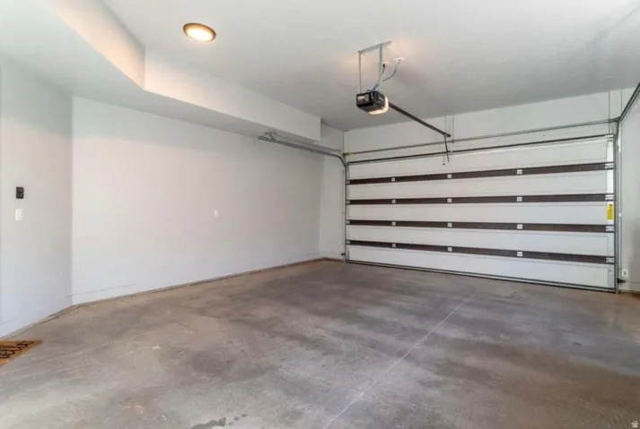 Attached garage with a concrete floor, overhead lighting, and an automatic garage door opener