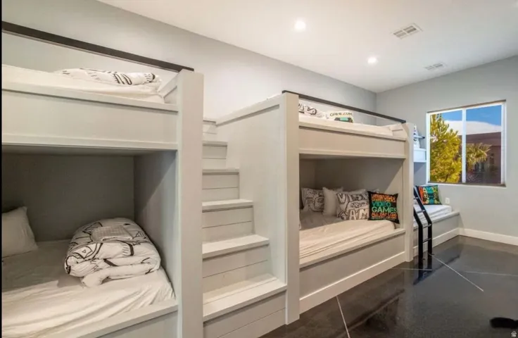 Built-in bunk beds with integrated staircase, window seat, recessed lighting, and dark-finish flooring