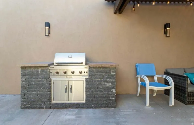 Outdoor kitchen featuring a built-in stainless steel grill with storage, stone-finish base, and a countertop