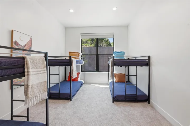 Spacious room featuring light-colored carpet flooring, recessed ceiling lights, and a large window with a dark frame