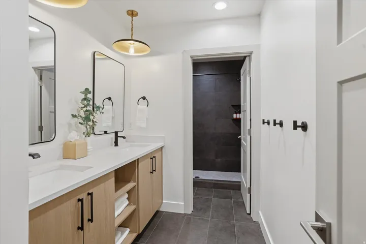 Dual vanity featuring light wood-finish cabinetry, integrated sinks, and matte black fixtures