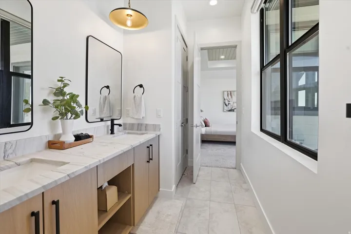 Double vanity with light wood-finish cabinetry, integrated sinks, and polished countertops