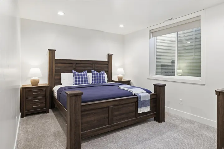 Spacious room featuring neutral carpeting, a large egress window with roller shade, recessed lighting, and white walls