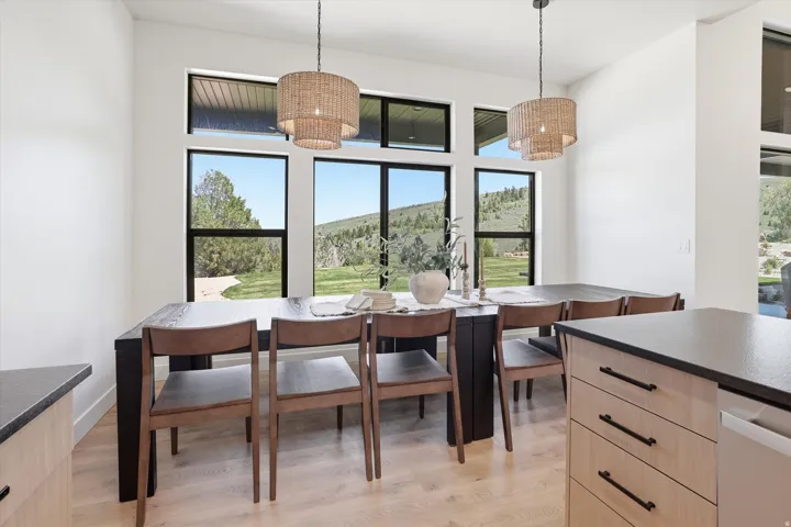 Dining area featuring multiple windows, two woven pendant lights, light wood-finish flooring, and a built-in kitchen island with light wood-finish cabinetry