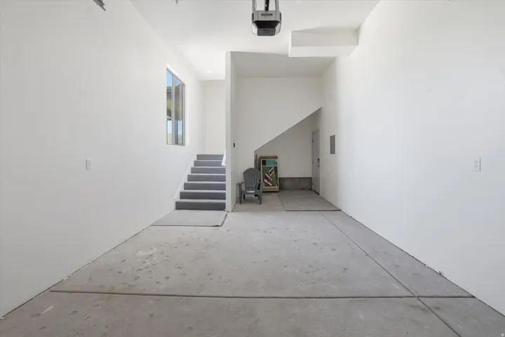 Spacious garage with concrete flooring, white painted walls, and an overhead garage door opener