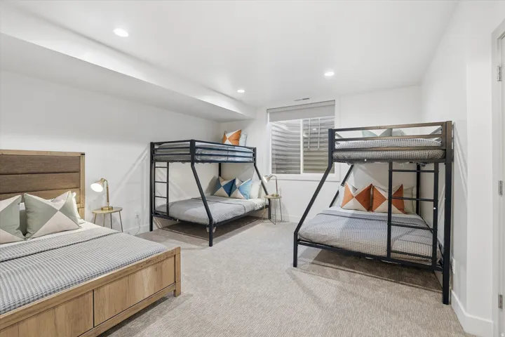 Carpeted bedroom with recessed lighting, a window with horizontal blinds, and a white door with a silver handle