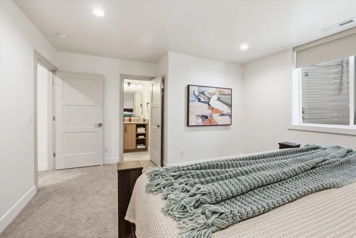 Carpeted bedroom featuring white walls, recessed lighting, and a window with a roller shade