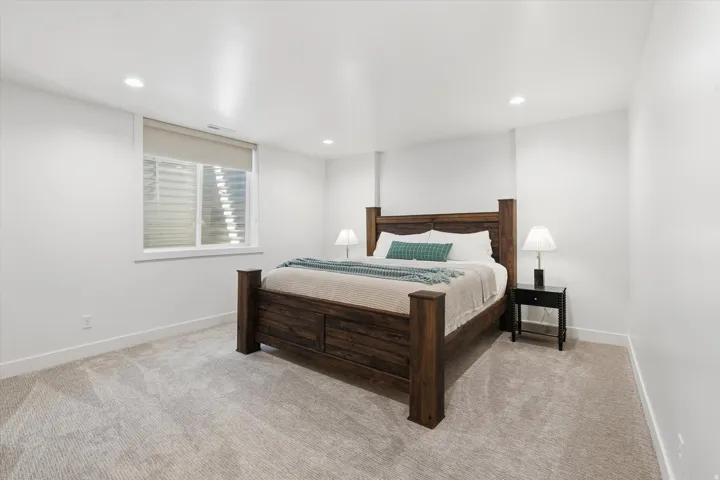 Spacious bedroom featuring light-toned carpet flooring, white walls, and recessed lighting