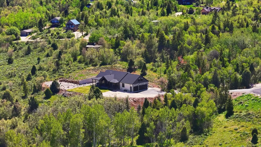 Modern ranch-style residence featuring a dark shingle roof, light-toned siding, and a two-car garage