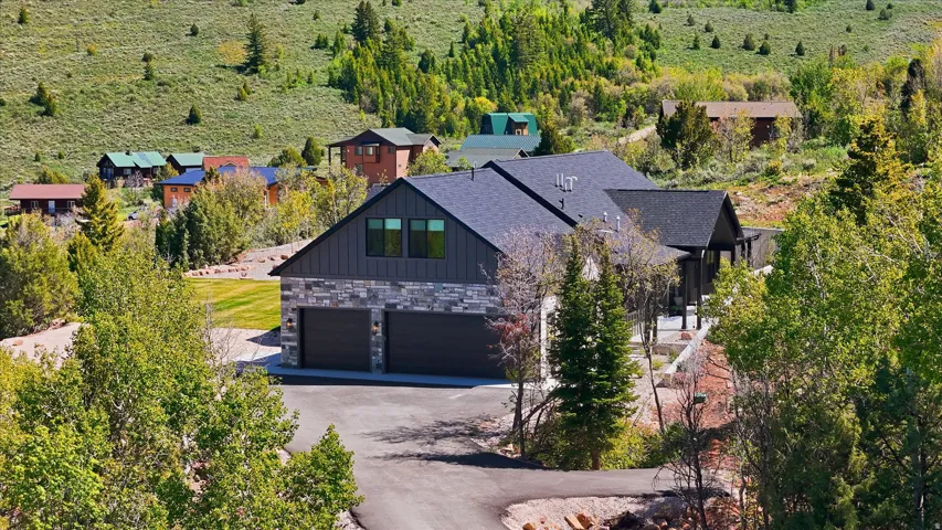 Contemporary home with a dark gray shingle roof, stone veneer, and vertical dark siding