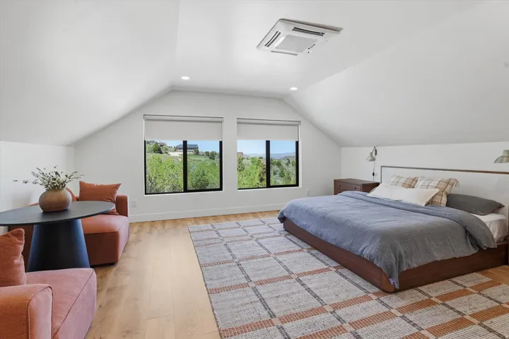 Spacious room featuring vaulted ceilings, a large area rug, and wood-finish flooring