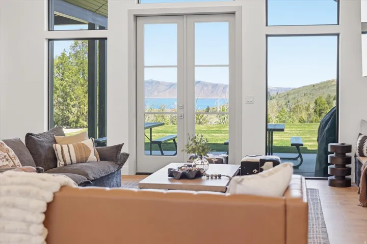 French doors opening to an expansive outdoor space with a distant water body and surrounding hills