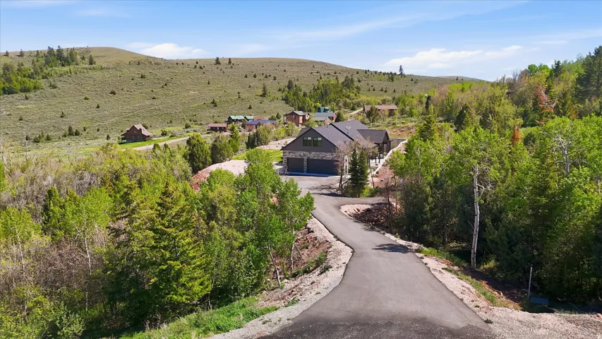 Modern mountain home featuring a dark gray roof, stone facade, and attached three-car garage