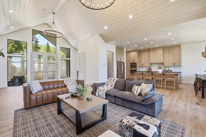 Open-concept living space featuring vaulted ceilings with wood-finish planks and recessed lighting