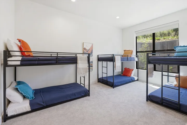 Spacious room featuring light gray carpeting, crisp white walls, recessed lighting, and a large window with black framing