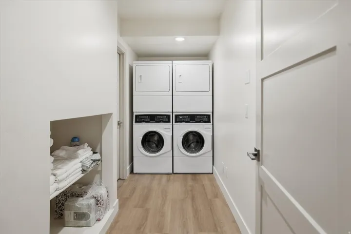 Dedicated laundry area featuring dual stacked washer and dryer units, wood-finish flooring, and recessed lighting