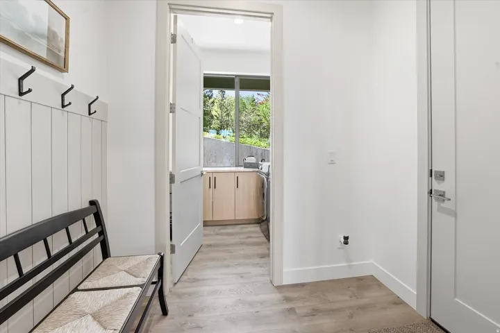 Entryway featuring a wainscoting accent wall with black coat hooks, wood-finish flooring, and a solid core door