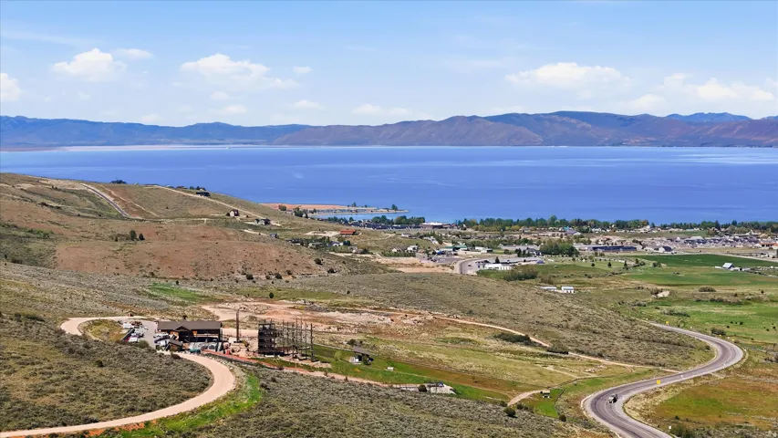 Expansive lakefront property featuring a serene body of water, distant mountain ranges, and an undulating landscape