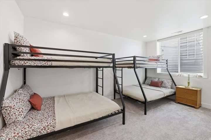 Spacious room featuring light gray carpeting and a large window with privacy blinds