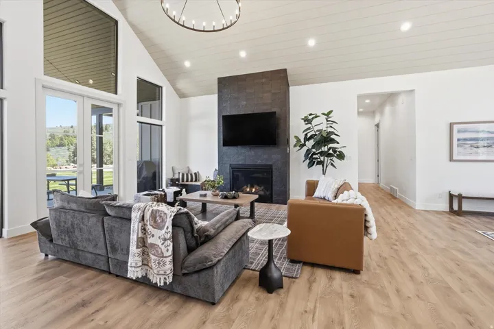 Spacious living area featuring a vaulted ceiling with wood-finish paneling, a contemporary chandelier, and recessed lighting