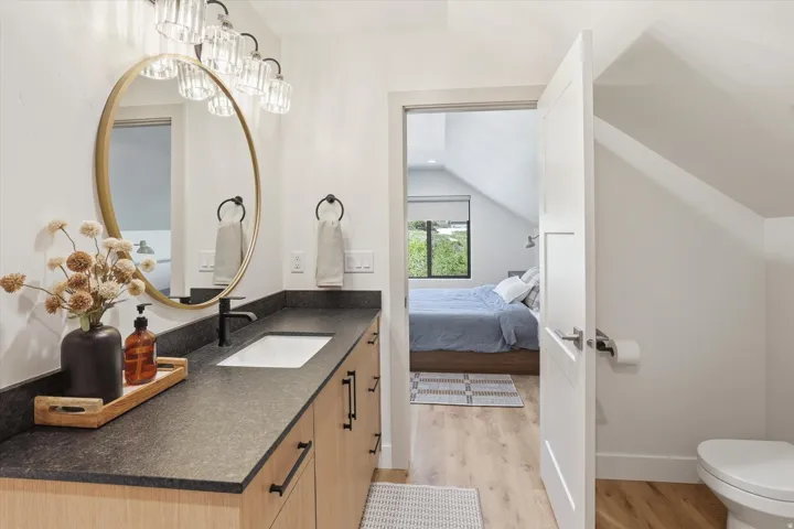 Bathroom vanity with an undermount sink, dark countertop, and light wood-finish cabinetry