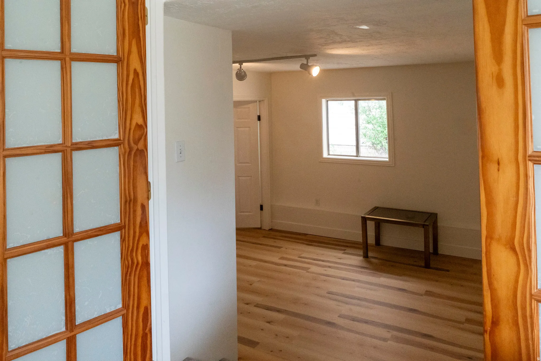 Room featuring light wood-finish flooring, white walls, and a window with exterior views